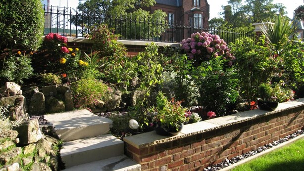 A brick pathway leading to a house with a well-maintained garden and a large tree. - The Winchester (Great Yarmouth)