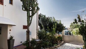 A building with a white exterior, a brick pillar, and a potted plant near the entrance. - 14 Leoni (Salerno)