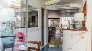 A hotel interior with a glass door displaying a large number '14', a dining area with tables and chairs, and a staircase leading to another floor. - 14 Leoni (Salerno)