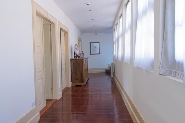 A hallway with wooden flooring, white walls, and a wooden cabinet with decorative items. - Casa do Monte (Baiao)
