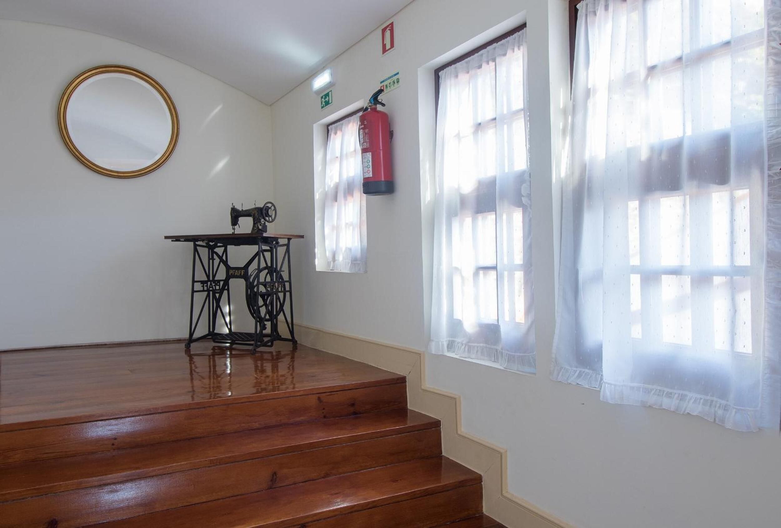 A room with a sewing machine, a fire extinguisher, and a mirror on the wall.
