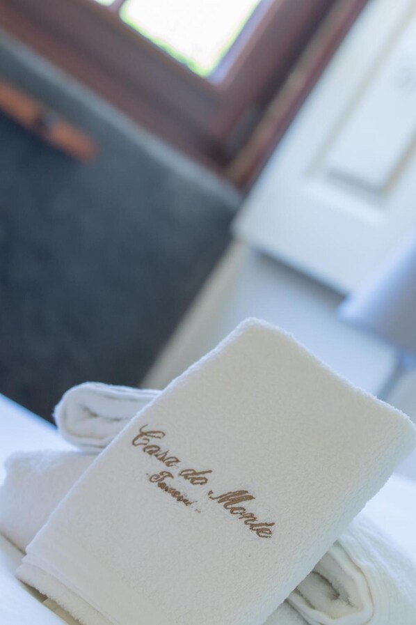 A neatly folded white towel with embossed text on a bed.