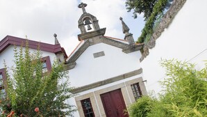 A white building with a red door, a bell tower, and a cross on top. - Casa do Monte (Baiao)