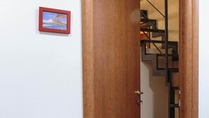 Una puerta de madera que da a una escalera con barandilla de metal.
