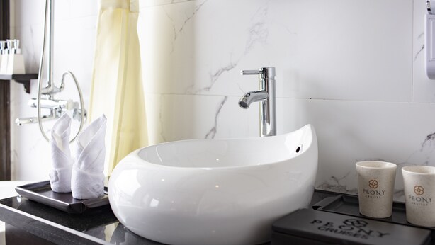 A bathroom with a white sink, a shower, and a towel rack. - Peony Cruises (Tuan Chau)