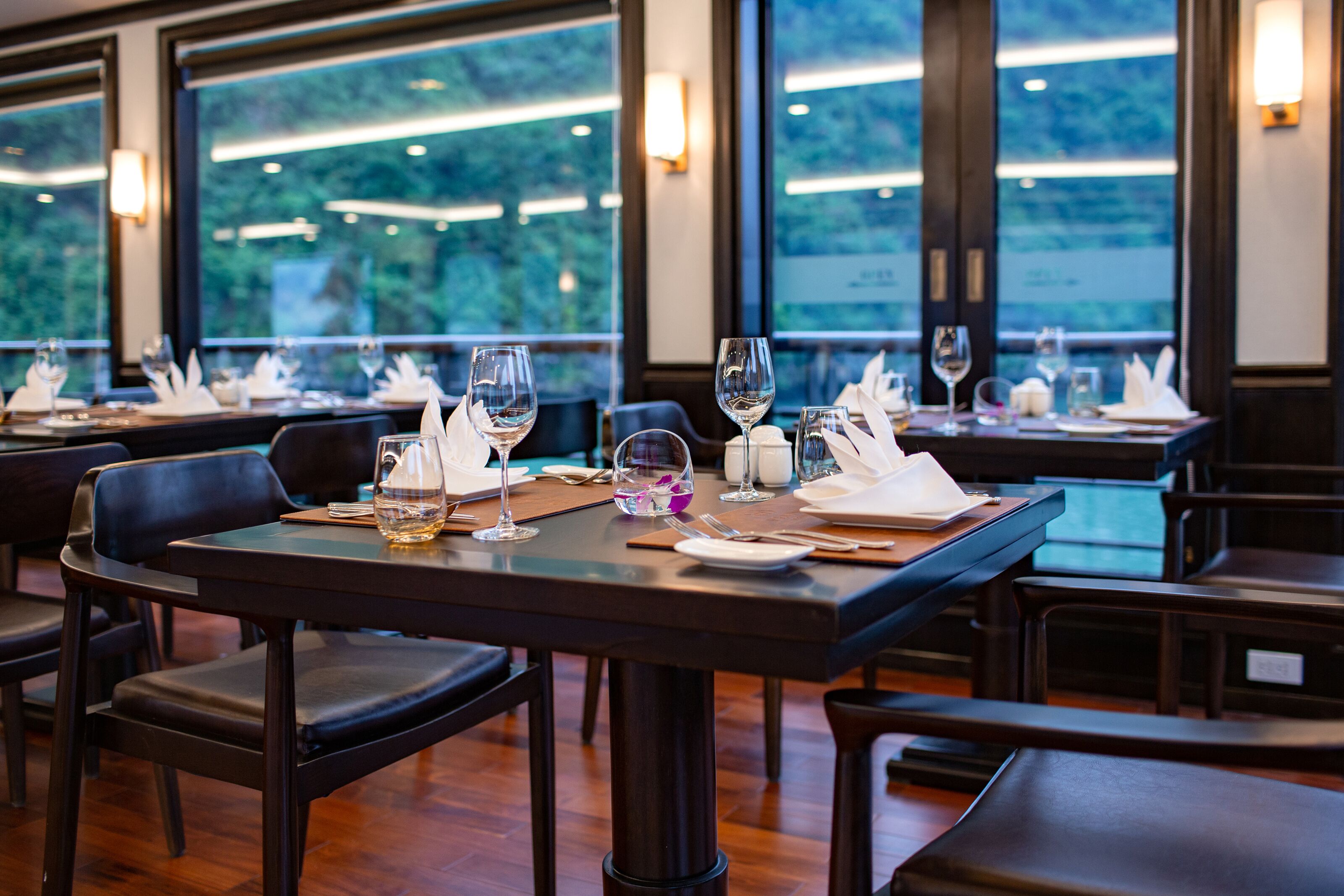 Restaurante con mesas dispuestas para comer, con vistas a zonas verdes a través de amplios ventanales.
