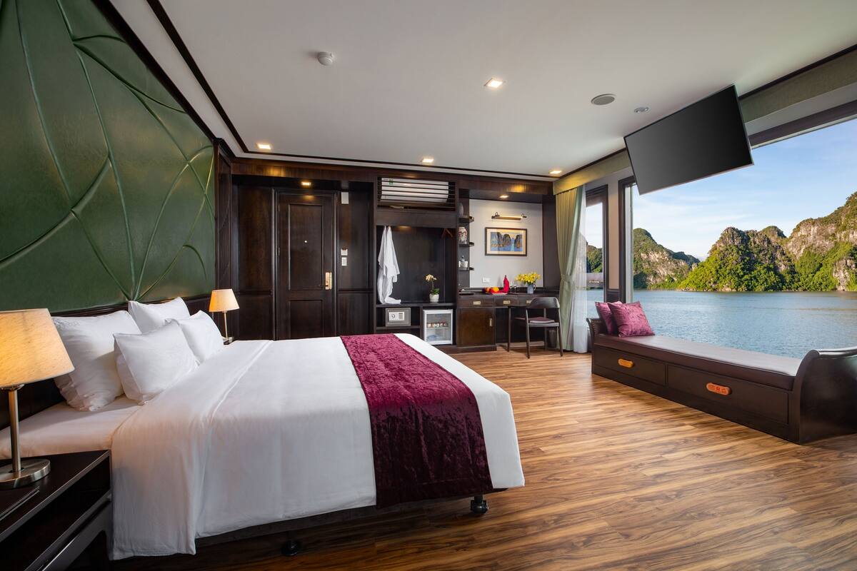 A modern hotel room with a large bed, a desk, a chair, and a view of a lake.