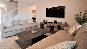 Ein modernes Wohnzimmer mit einer Couch, einem Couchtisch und einem an der Wand befestigten Fernseher.