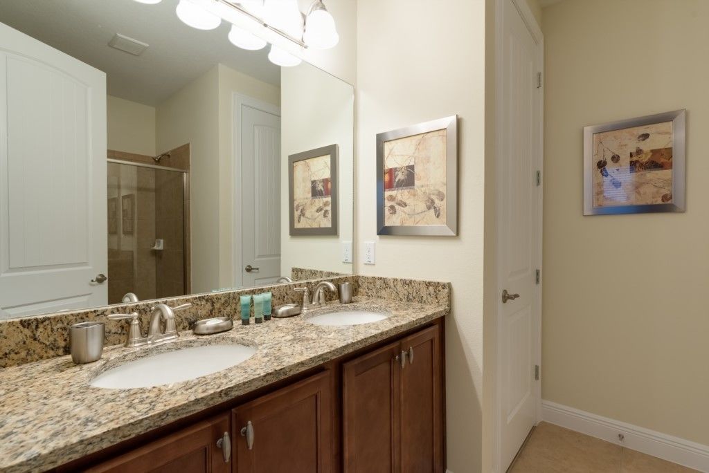 A bathroom with two sinks, a large mirror, and framed artwork on the wall.