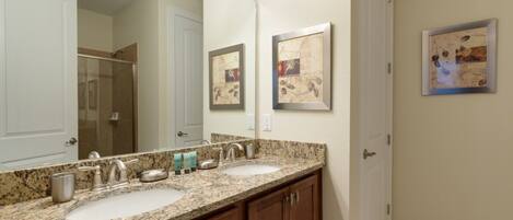 A bathroom with two sinks, a large mirror, and framed artwork on the wall.