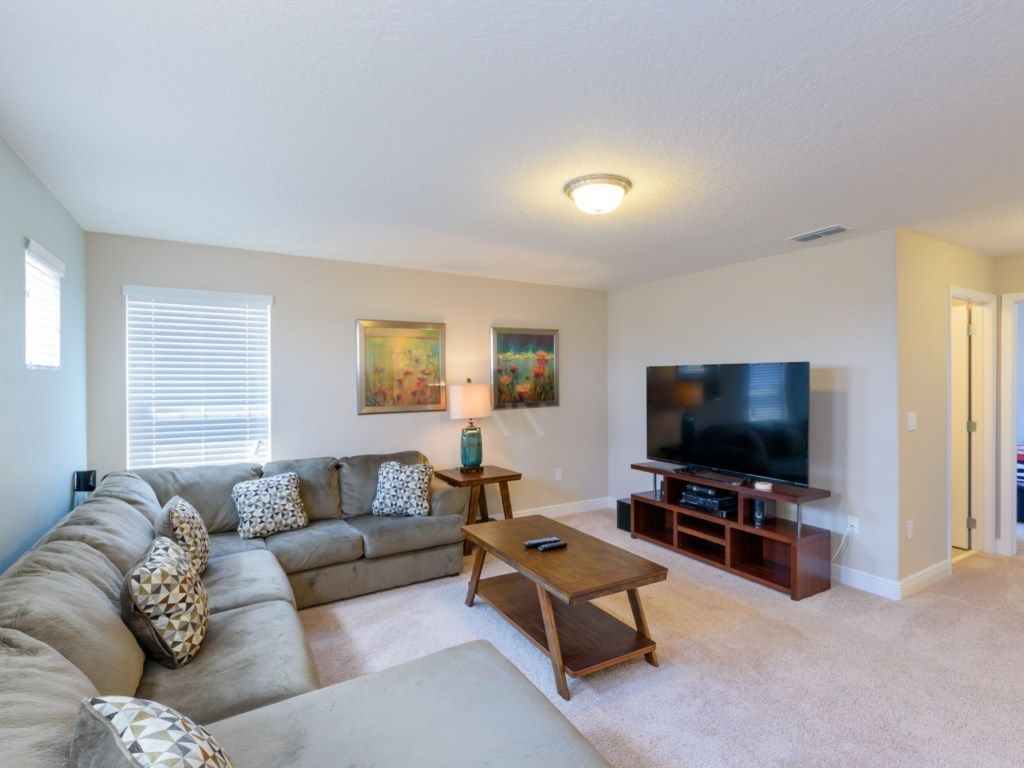 A living room with a sofa, coffee table, TV, and artwork on the wall.