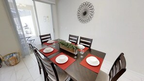 A dining room with a dark wooden table, four chairs, and a decorative metal wall piece. - Aco256584 - Storey Lake Resort - 4 Bed 3 Baths Townhome (Kissimmee)