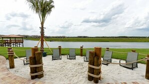Une plage de sable avec des chaises longues et une barrière en corde, d’où l’on peut admirer un plan d’eau et des bâtiments situés au loin.