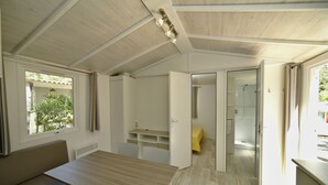 A compact, modern interior with a dining area, a small kitchenette, and a shower. - Village Camping  de l'Ostriconi (Palasca)