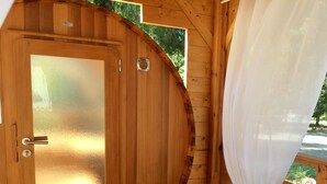 A wooden sauna with a glass door, a bench, and a curtain. - Village Camping  de l'Ostriconi (Palasca)