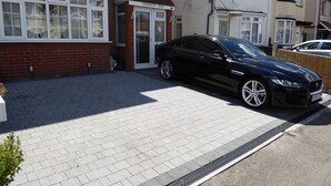 A black car parked in front of a house with a red brick facade and a white door. - Shenandoah House (Margate)