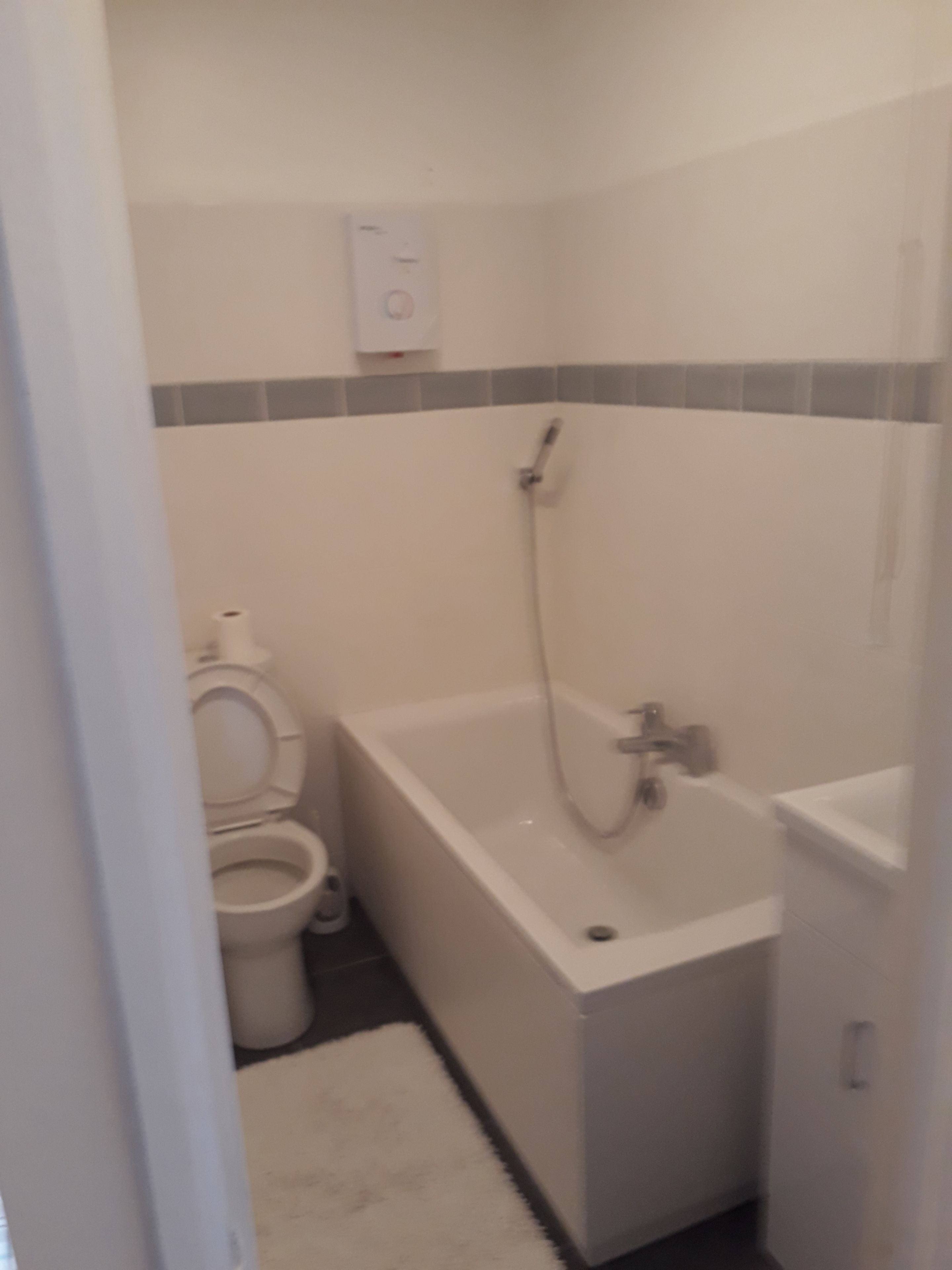 Un bany petit amb vàter, banyera i plat de dutxa.
