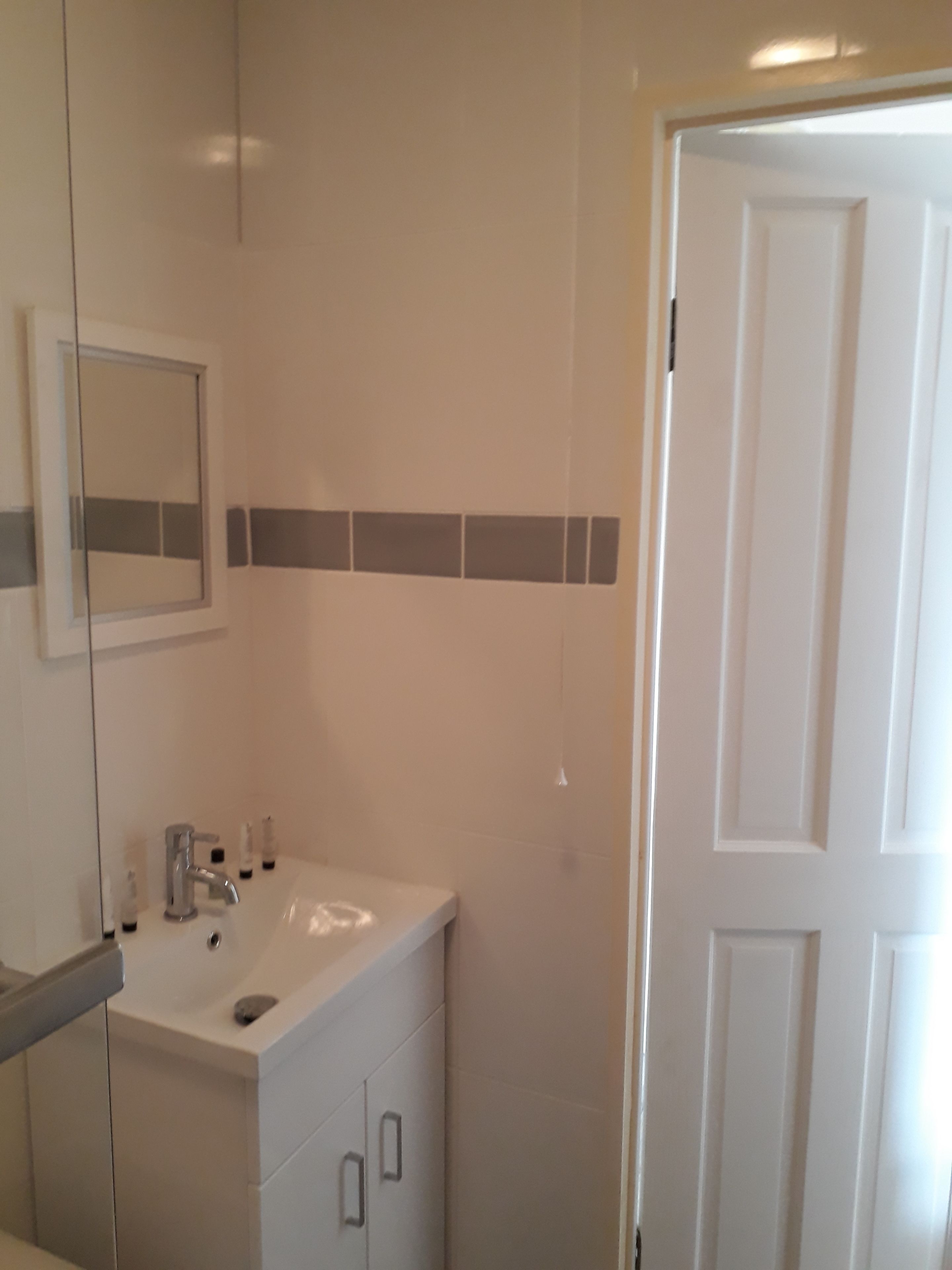 A bathroom with a white sink, mirror, and cabinet.