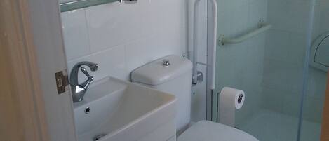 A modern bathroom with a toilet, sink, and glass-enclosed shower.