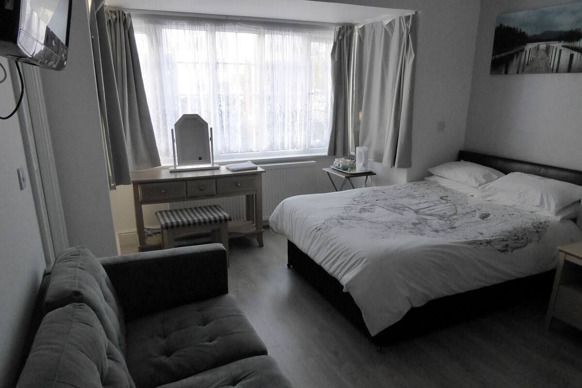A bedroom with a bed, a bench, a desk, and a chair.