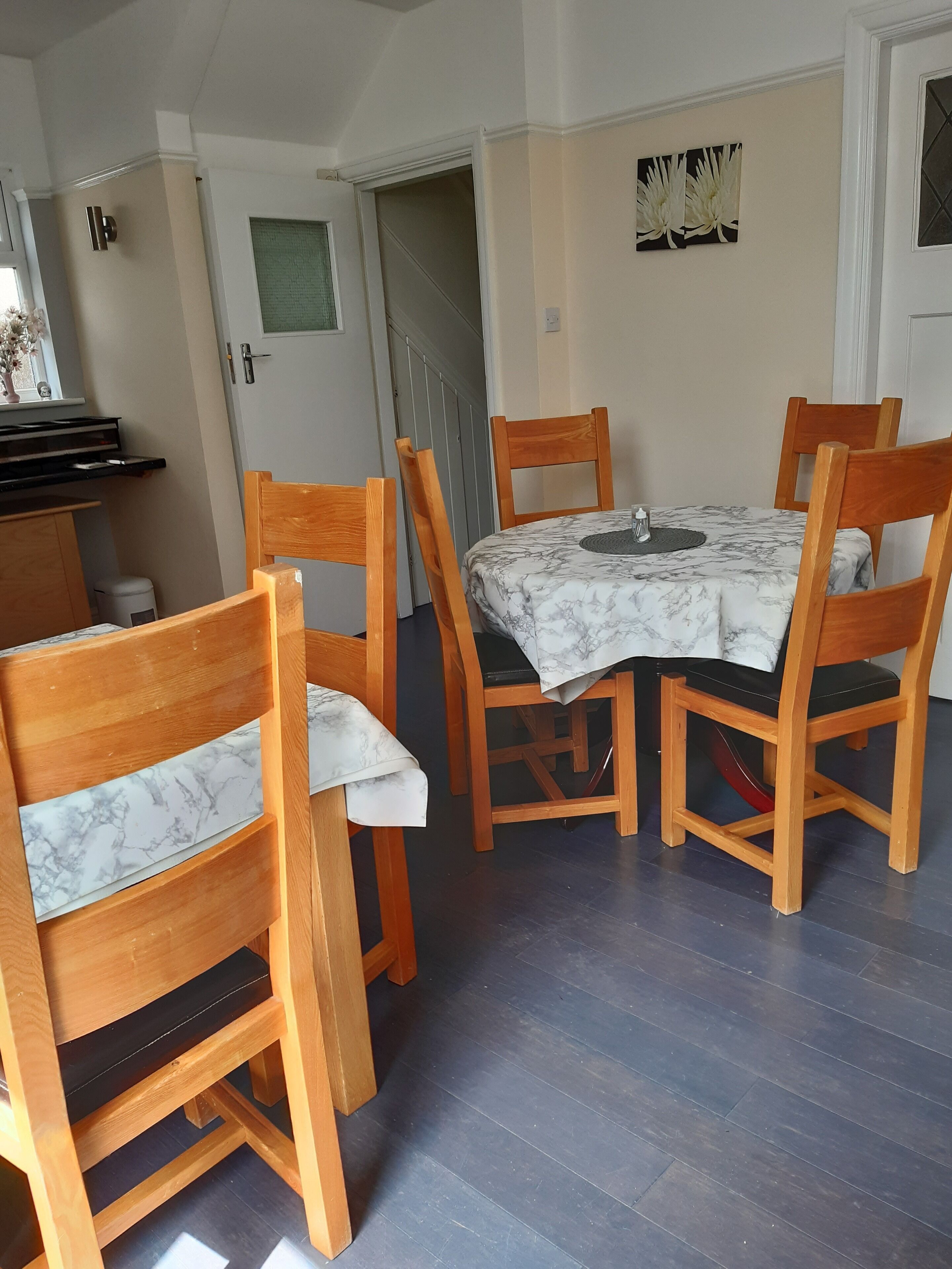 Ein Essbereich mit einem für vier Personen gedeckten Tisch, umgeben von Holzstühlen mit gepolsterten Sitzen.