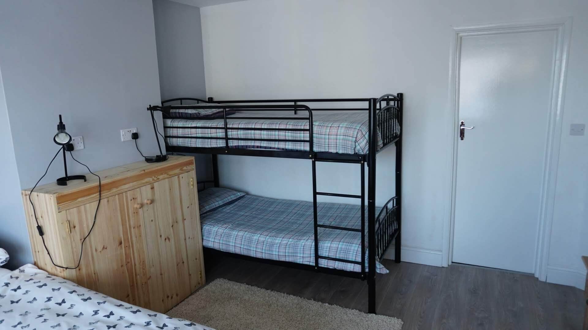 Dormitorio con literas, un aparador de madera y un escritorio con lámpara.