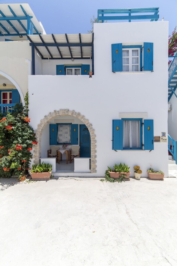A white building with blue shutters and a stone archway.