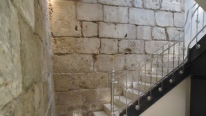 A staircase with a metal railing, a stone wall, and a tiled floor with a geometric pattern. - Apartamentos Turisticos Mauror (Granada)