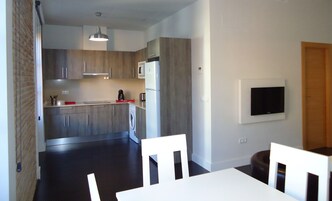 Una cocina moderna con armarios de madera, microondas y refrigerador. Hay un comedor con mesa y sillas.