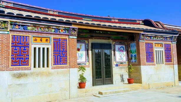 Un edificio tradicional con ornamentadas decoraciones azules y rojas, tejado de tejas y entrada con mosaicos.