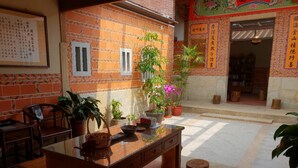 Un patio tradicional chino con una mesa de madera, plantas en macetas y un piso de baldosas.