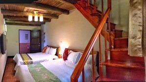 Un dormitorio con dos camas, una escalera de madera y una pared de ladrillo.