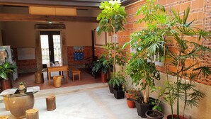 Un espacio interior acogedor, con pared de ladrillo, muebles de madera y varias plantas en macetas.