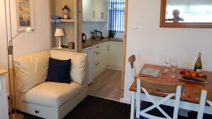 A cozy living area with a sofa, a dining table with chairs, a lamp, and a kitchen in the background. - Dartmouth Chalet Holidays (Dartmouth)