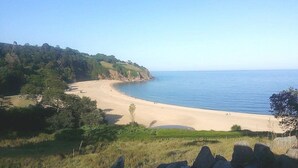 A coastal landscape with a sandy beach, green hills, and a clear sky. - Dartmouth Chalet Holidays (Dartmouth)