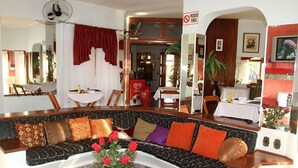A living room with a sofa, a coffee table with a flower arrangement, and a dining area with a table and chairs. - Pousada Sorocaba (Sorocaba)