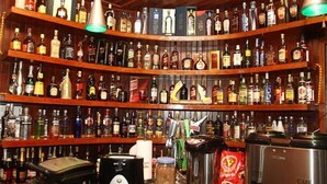 A bar with multiple shelves of liquor bottles, a coffee machine, and a coffee grinder. - Pousada Sorocaba (Sorocaba)