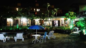 An outdoor patio area with lounge chairs, a table, and an umbrella. - Pousada Sorocaba (Sorocaba)