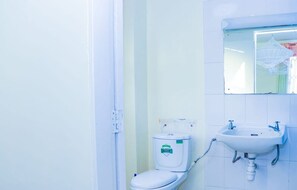 A small bathroom with a toilet and a wall-mounted sink. - Blossom Apartment (Nairobi)