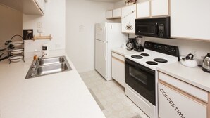 A modern kitchen with white cabinets, a black microwave, a stove, and a sink. - Ip60497 - Island Club West - 3 Bed 2 Baths Condo (Kissimmee)