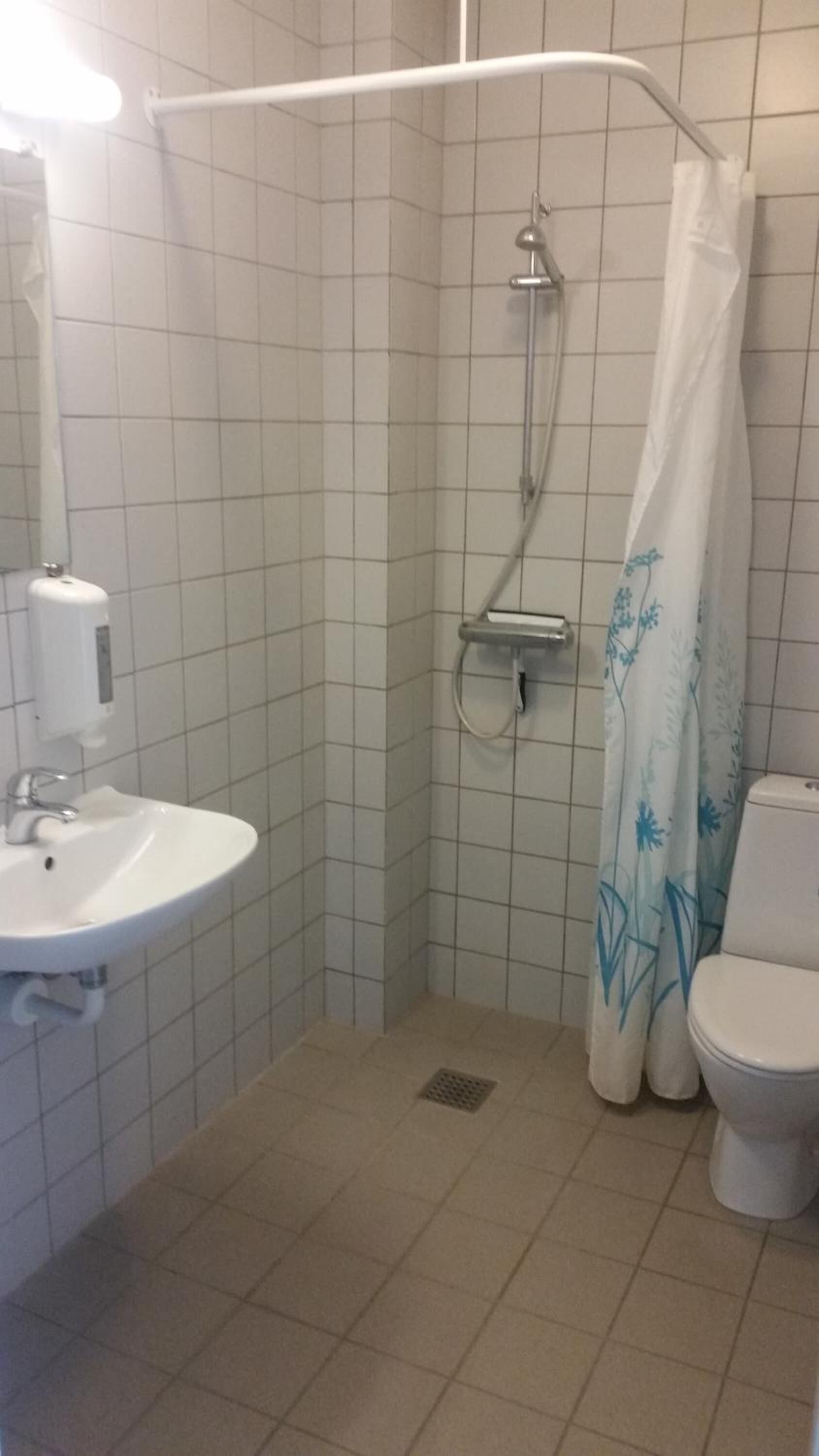 Ein kleines Badezimmer mit Fliesen, einer Dusche, einer Toilette und einem Waschbecken.