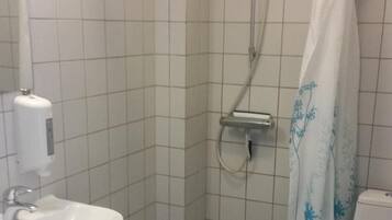Ein kleines Badezimmer mit Fliesen, einer Dusche, einer Toilette und einem Waschbecken.