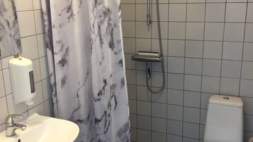 A bathroom with a white sink, toilet, and shower.