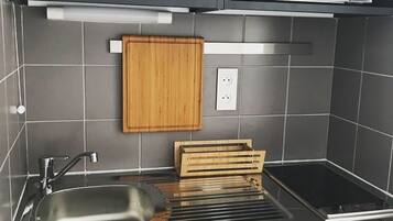 Een moderne keuken met een roestvrijstalen spoelbak, een houten snijplank en een inbouwmagnetron.