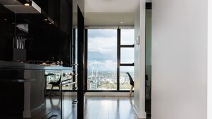 A modern kitchen with a large window, a view of the city, and a wooden floor. - Executive Stay on Little Collins (Melbourne)