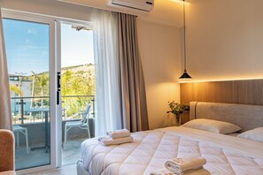 Une chambre d’hôtel avec un lit, un balcon avec des chaises et une vue sur l’extérieur.