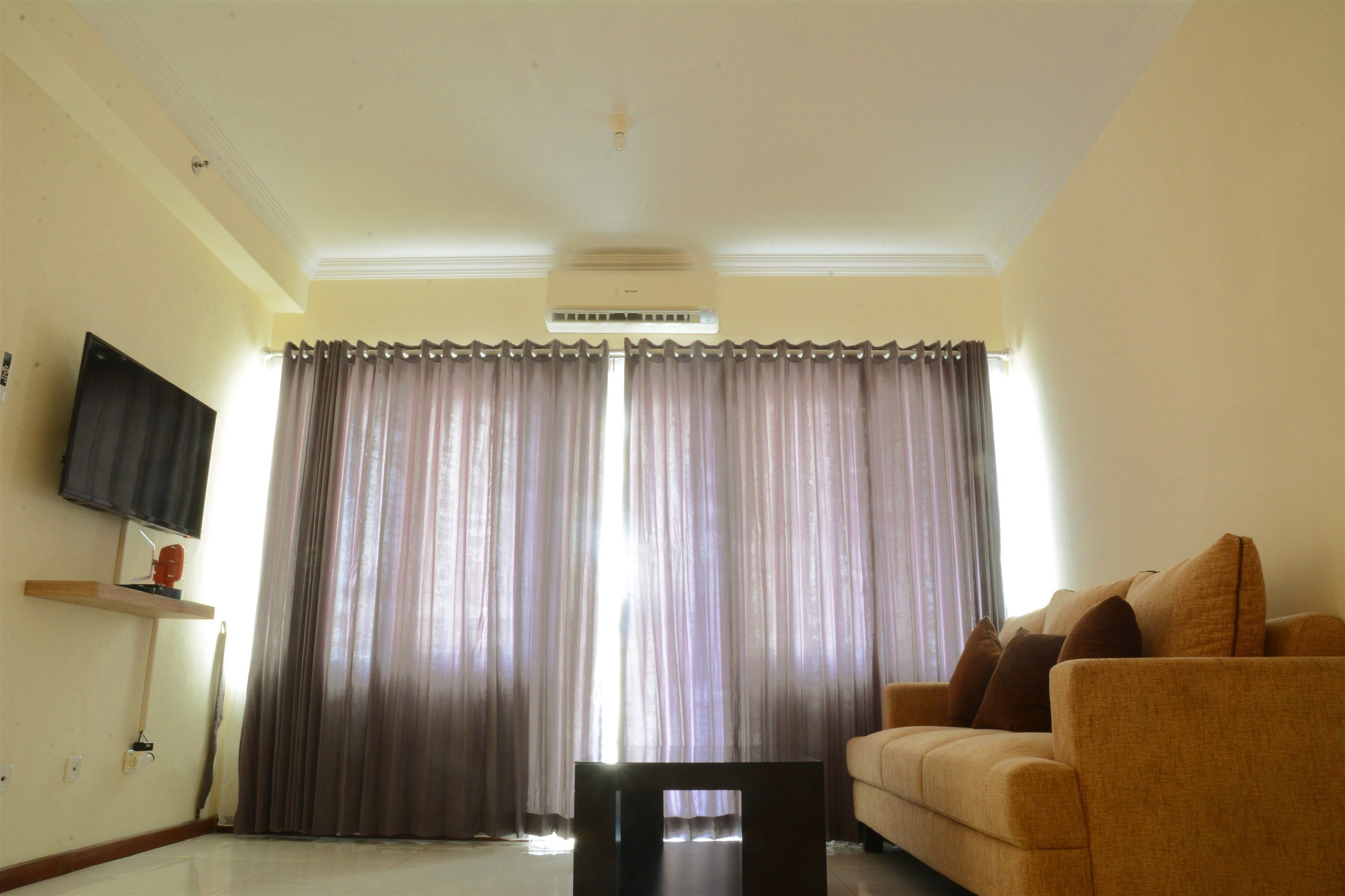 A living room with a sofa, a coffee table, and a flat-screen TV mounted on the wall.