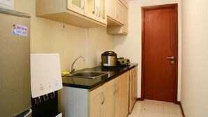 A compact kitchen with a refrigerator, a water dispenser, a sink, and a stove. - New And Modern Grand Palace Kemayoran Apartment (Jakarta)