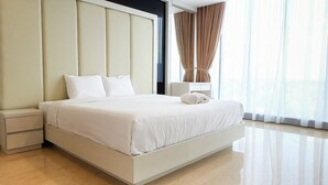 A modern hotel room with a large bed, a nightstand, and a bedside table. - Best North L'Avenue Apartment (Jakarta)