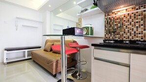 A modern kitchen with a beige countertop, a gas stove, and a tiled backsplash. - Affordable Bassura City Apartment (Jakarta)